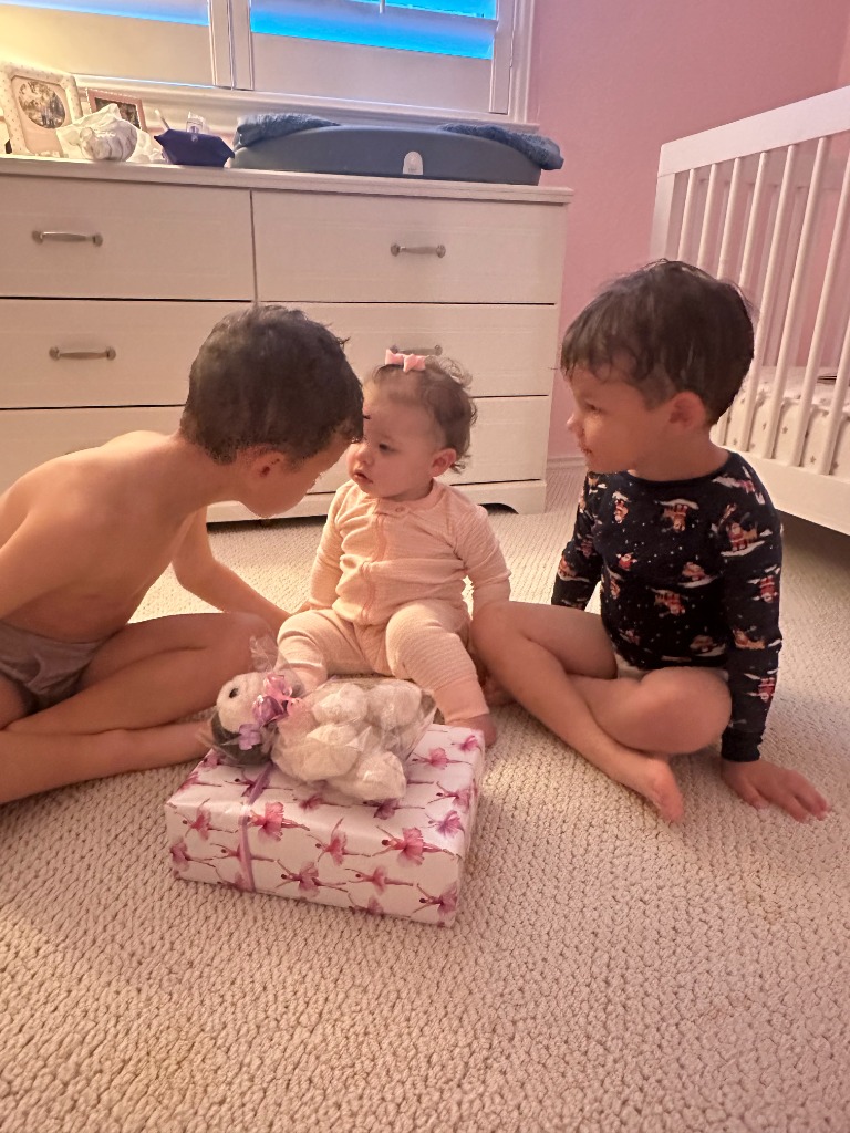 Luke's three children sitting together in a nursery with a gift
